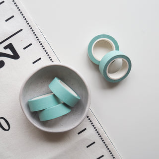 Two rolls of light blue tape on a white surface with a ruler in the background.
