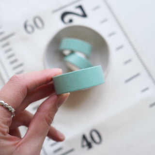 Hand holding a roll of light blue tape
