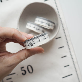 A hand holding a single washi measuring tape 