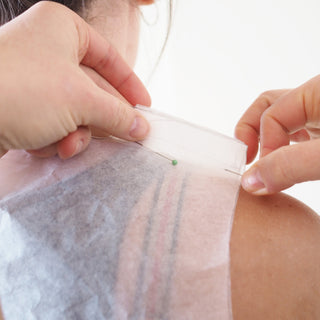 A toile made from patterntrace swedish tracing paper being pinned on to a real persons shoulder